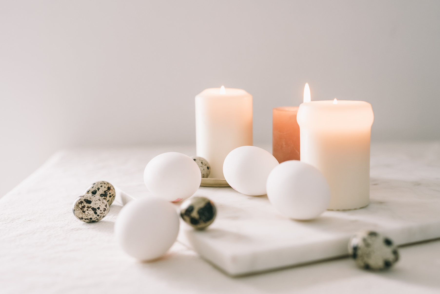 White Eggs And Quail Eggs Beside Lighted Candles